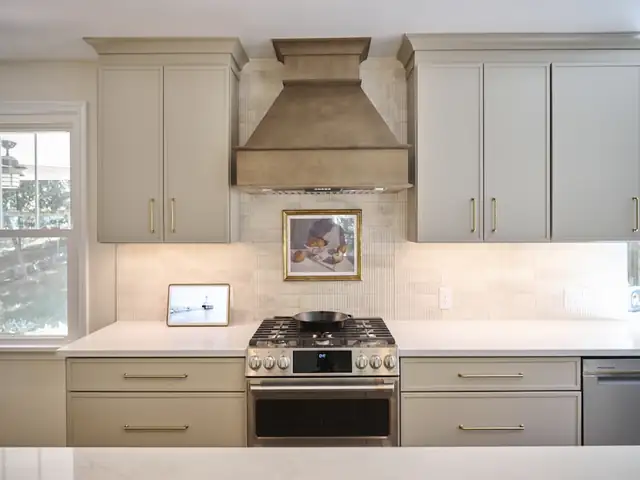 St. Louis area kitchen remodel with white veined waterfall island, brass lantern pendants and stained wood upper cabinets