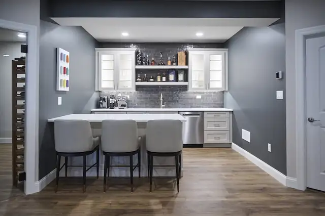 Kitchen with greige shaker cabinets, tapered plaster-look range hood, gas range and stone-look tile backsplash